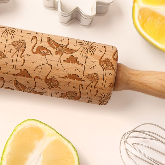 Wooden rolling pin with flamingo designs on a kitchen counter with lemons and a whisk.