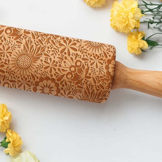 Wooden rolling pin with floral patterns on a white background with yellow flowers.