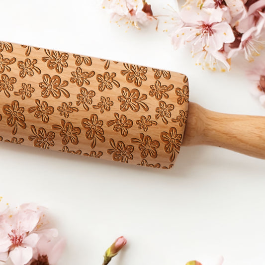 Wooden rolling pin with floral patterns on a white background with cherry blossoms.