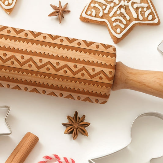 Wooden embossing rolling pin with star anise and cookies on a white surface