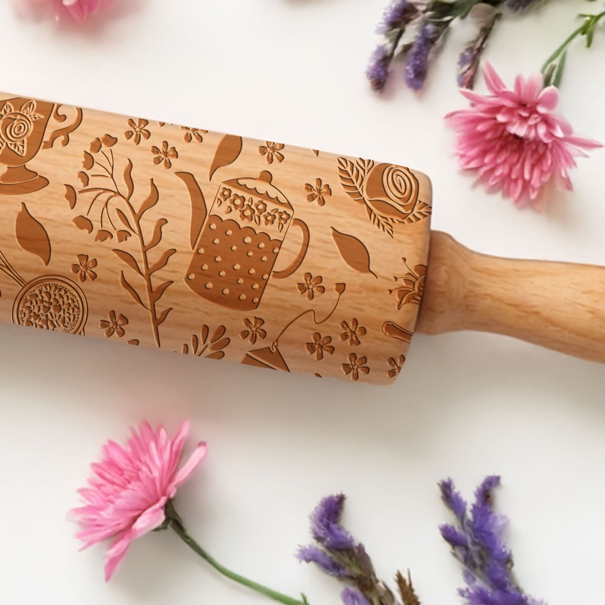 Wooden rolling pin with floral and teacup patterns on a white background with flowers.