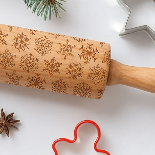Wooden rolling pin with snowflake patterns on a white surface with baking tools.