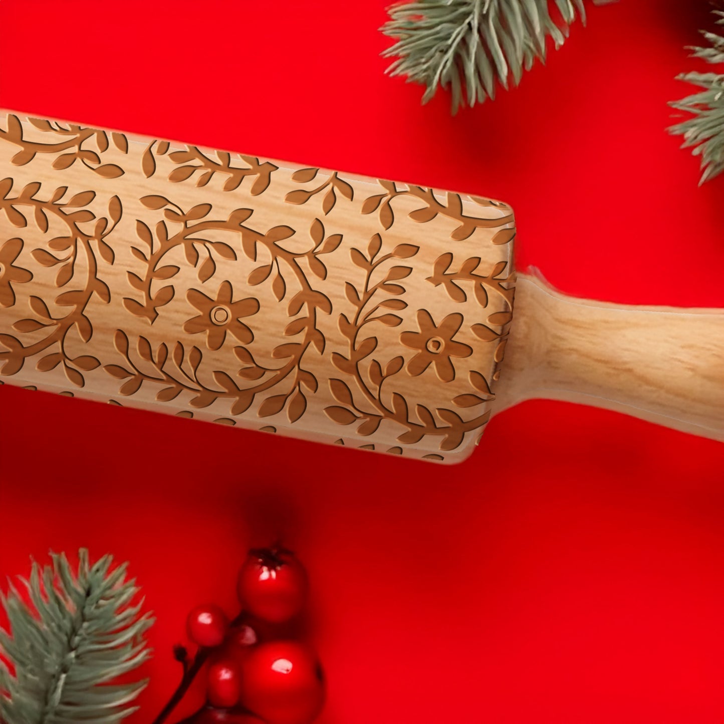 Wooden rolling pin with floral patterns on a red background with Christmas decorations.