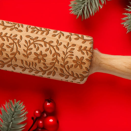 Wooden rolling pin with floral patterns on a red background with Christmas decorations.