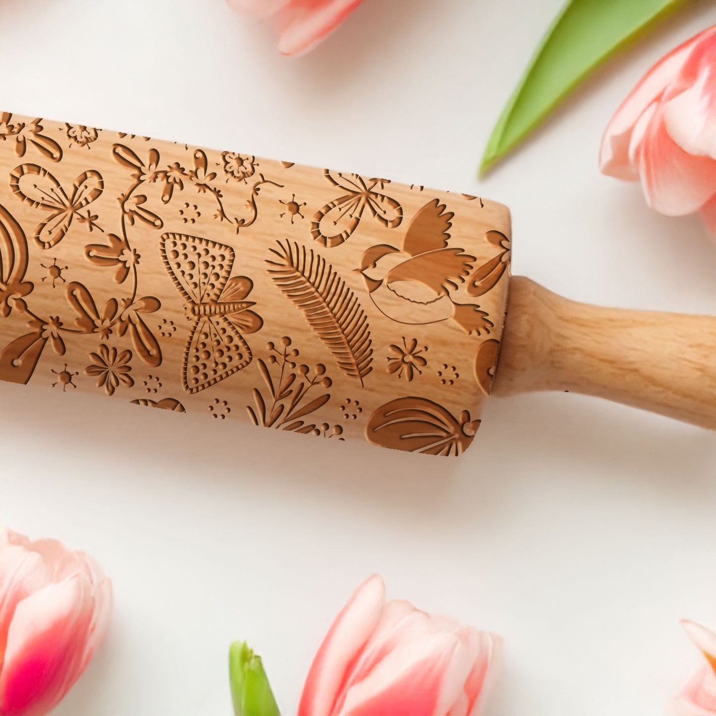 Wooden embossing rolling pin with floral patterns on a light background with tulips.