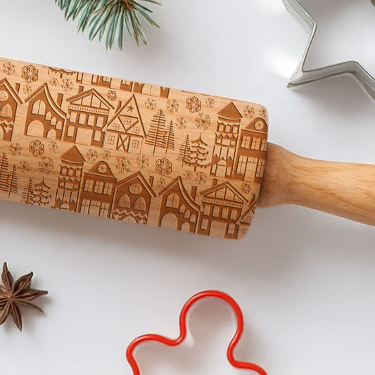 Wooden rolling pin with embossed designs on a white surface with cookie cutters and spices.