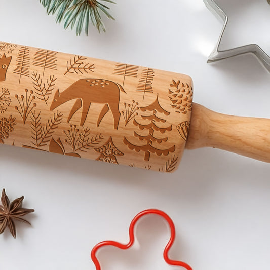 Wooden rolling pin with embossed designs on a white surface with cookie cutters.