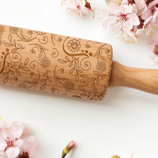 Wooden rolling pin with floral patterns on a white background with cherry blossoms.