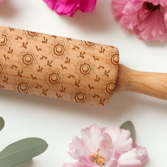 Wooden rolling pin with floral patterns on a white background with pink flowers.