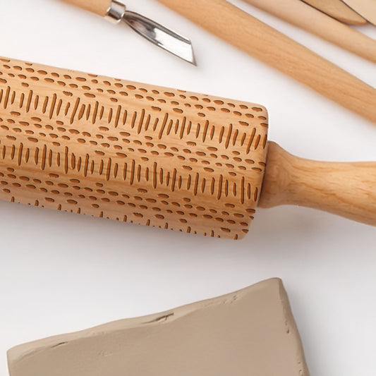 Wooden rolling pin with embossed pattern on a white background