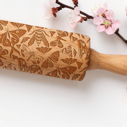 Wooden rolling pin with butterfly patterns on a white background with cherry blossoms.