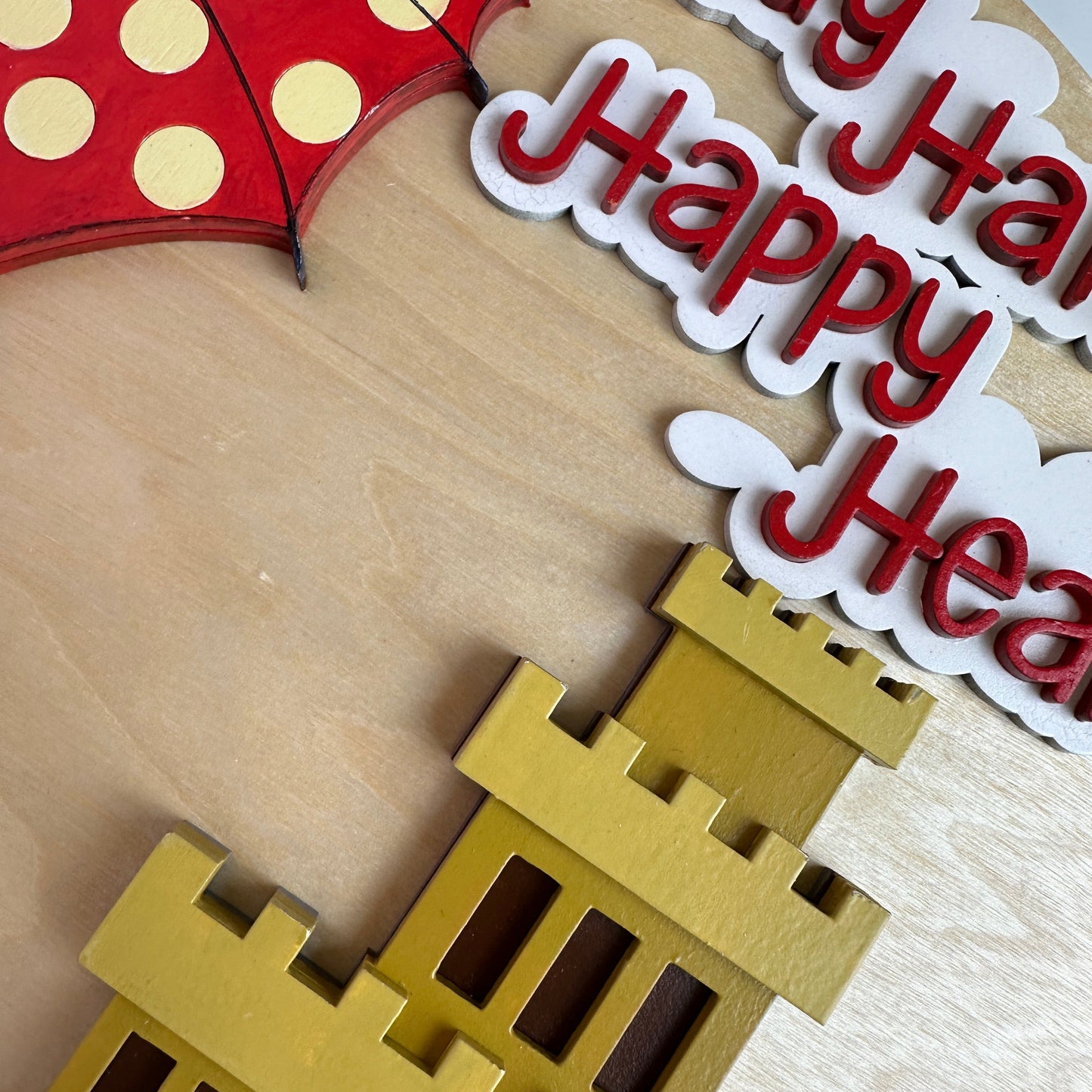 Decorative cutout with castle, umbrella, and text on a wooden surface