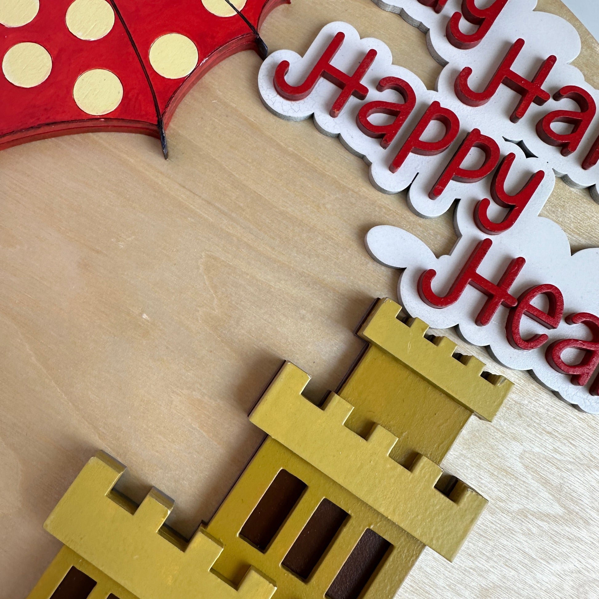 Decorative cutout with castle, umbrella, and text on a wooden surface