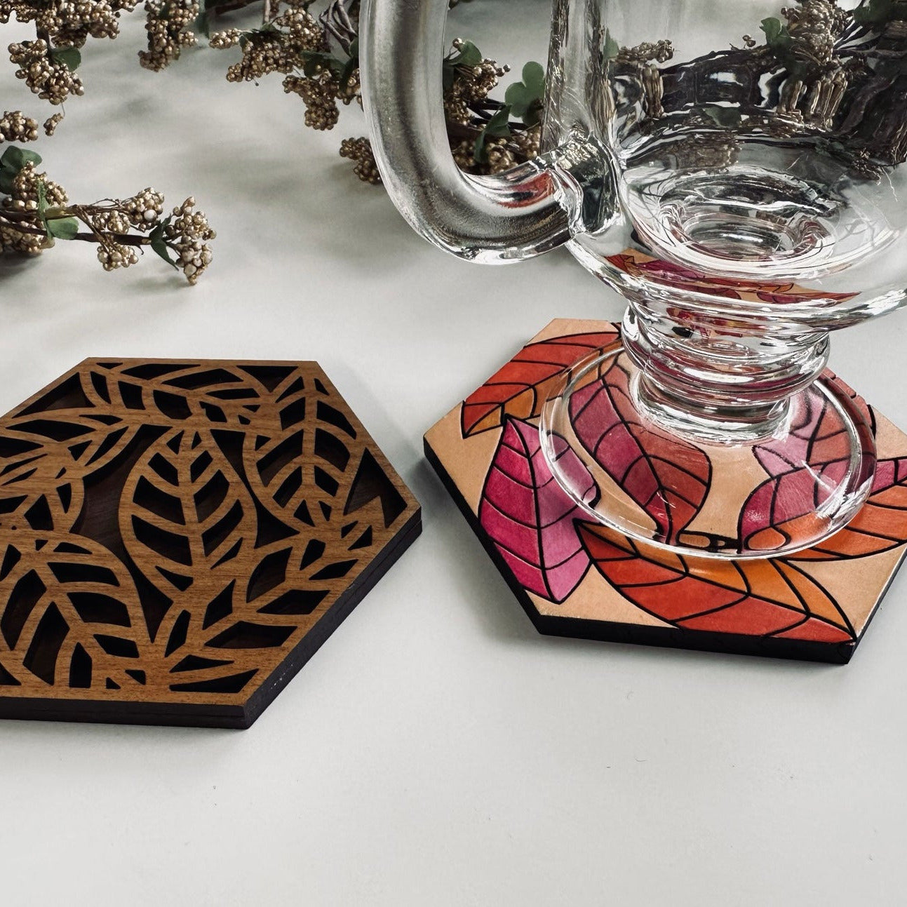 Glass mug on a coaster with a leaf design on a white background