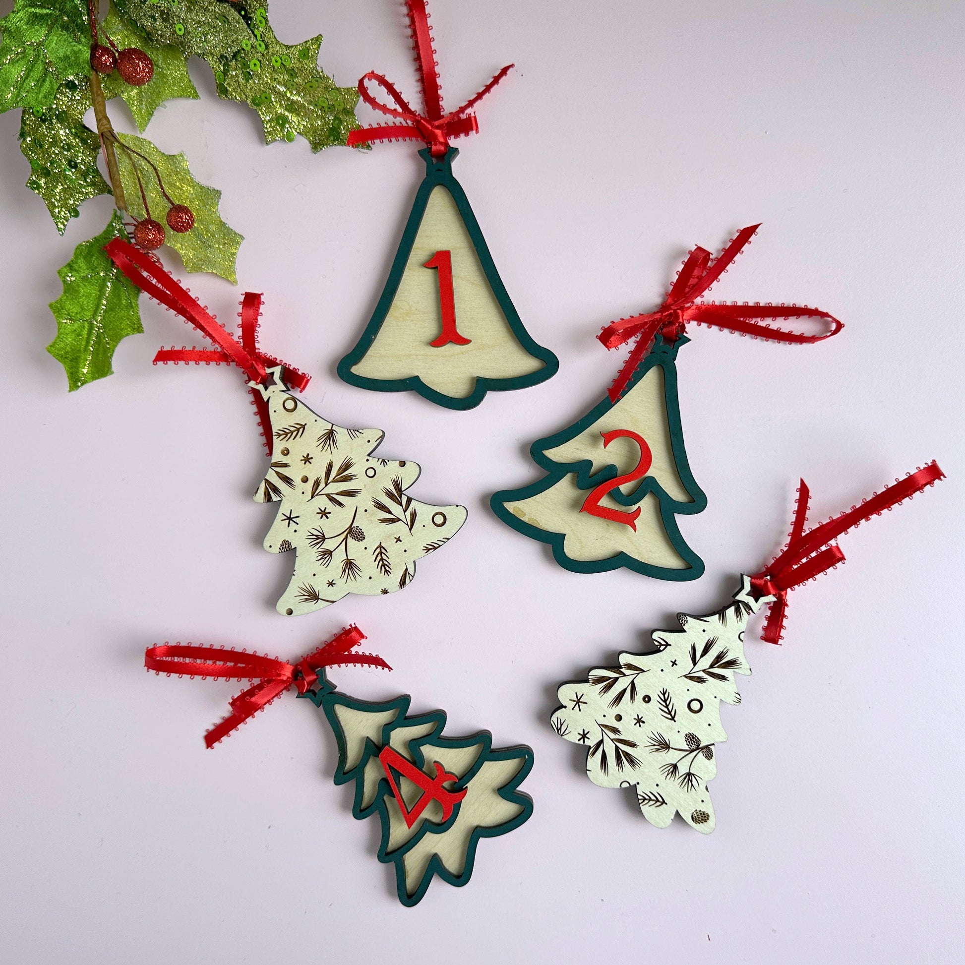 Laser-cut layered Christmas tree ornaments with red ribbon bows, hanging against a holiday backdrop