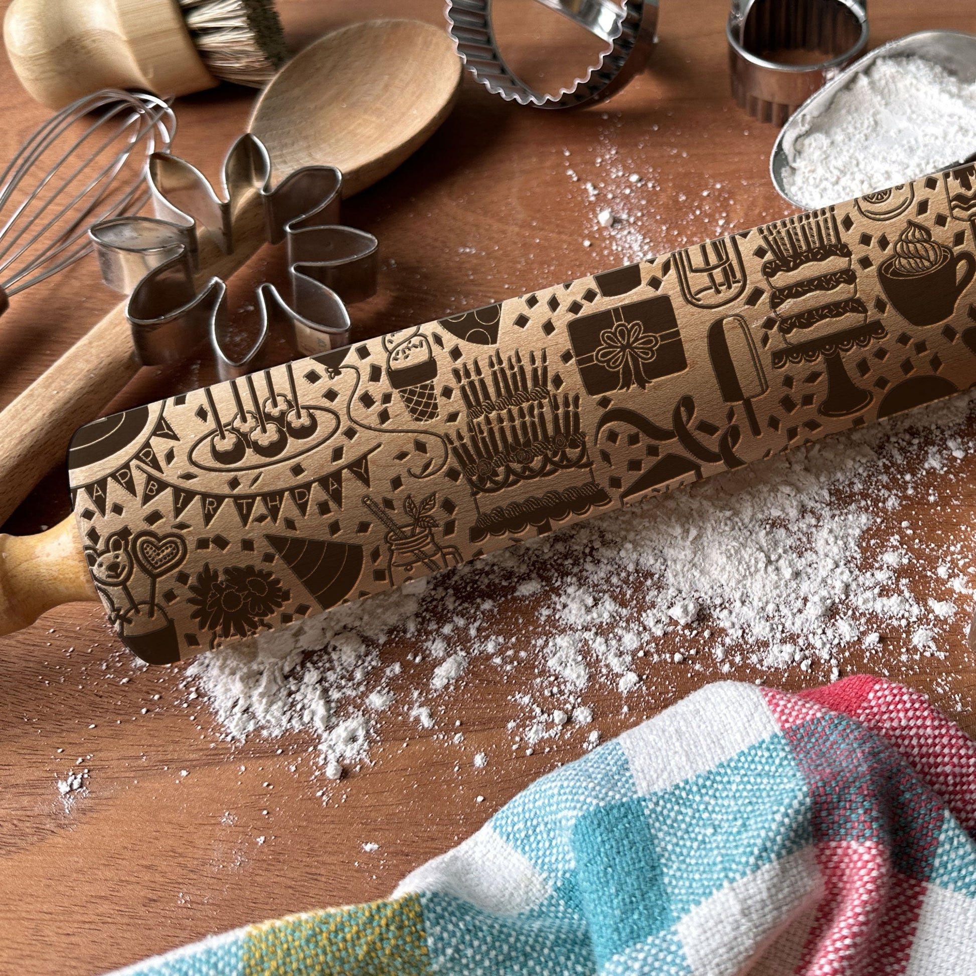 Decorative rolling pin with embossed designs on a wooden surface with baking tools.