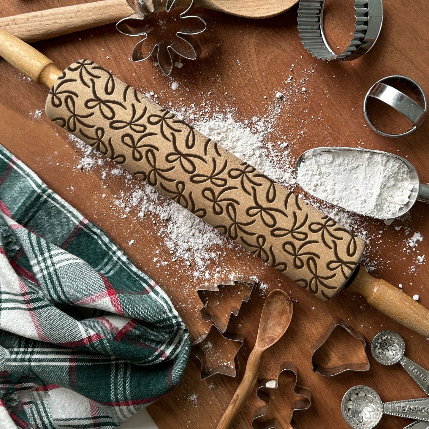 Wooden rolling pin with embossed pattern on a wooden surface with baking tools and flour.
