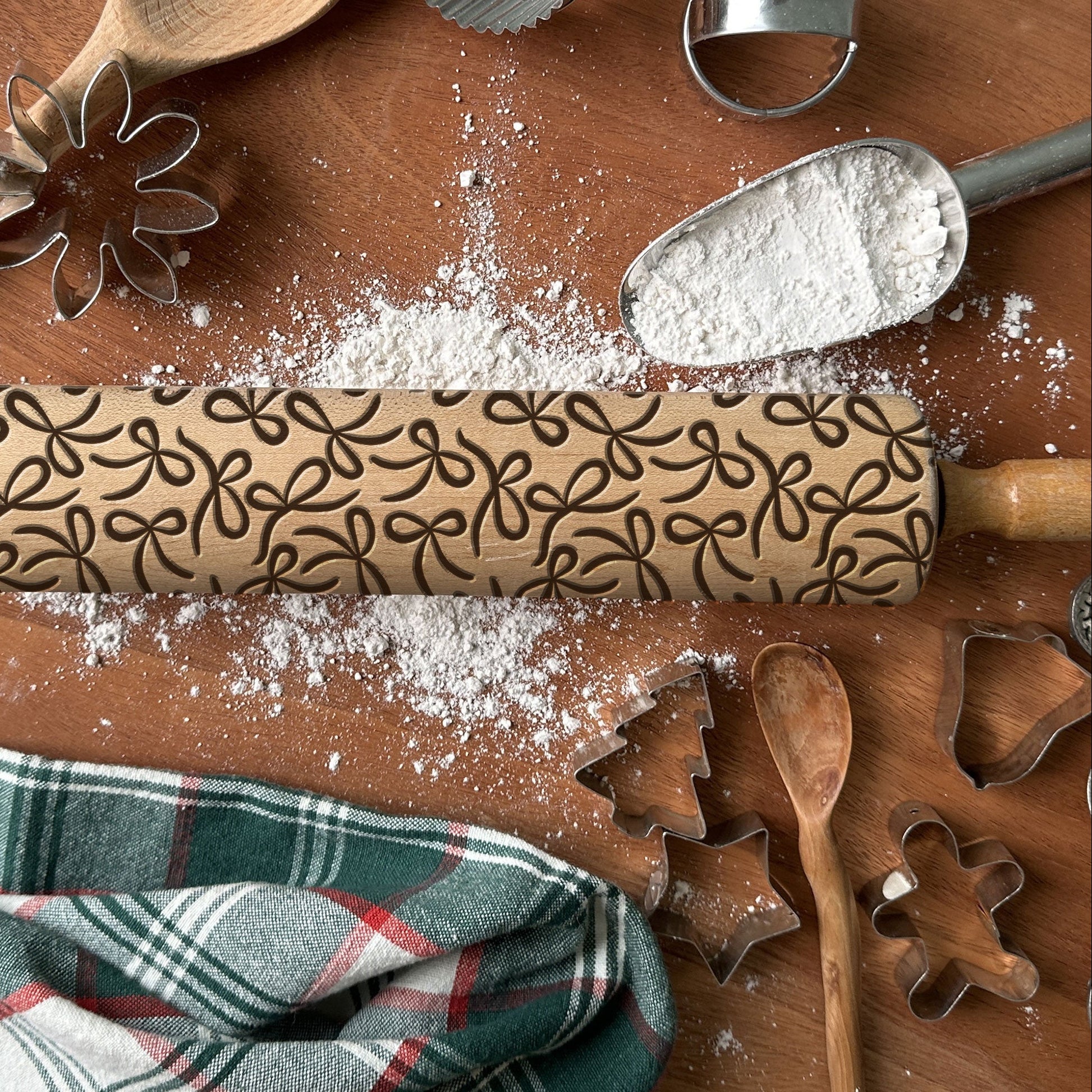 Decorative rolling pin with embossed patterns on a wooden surface with baking tools and flour.