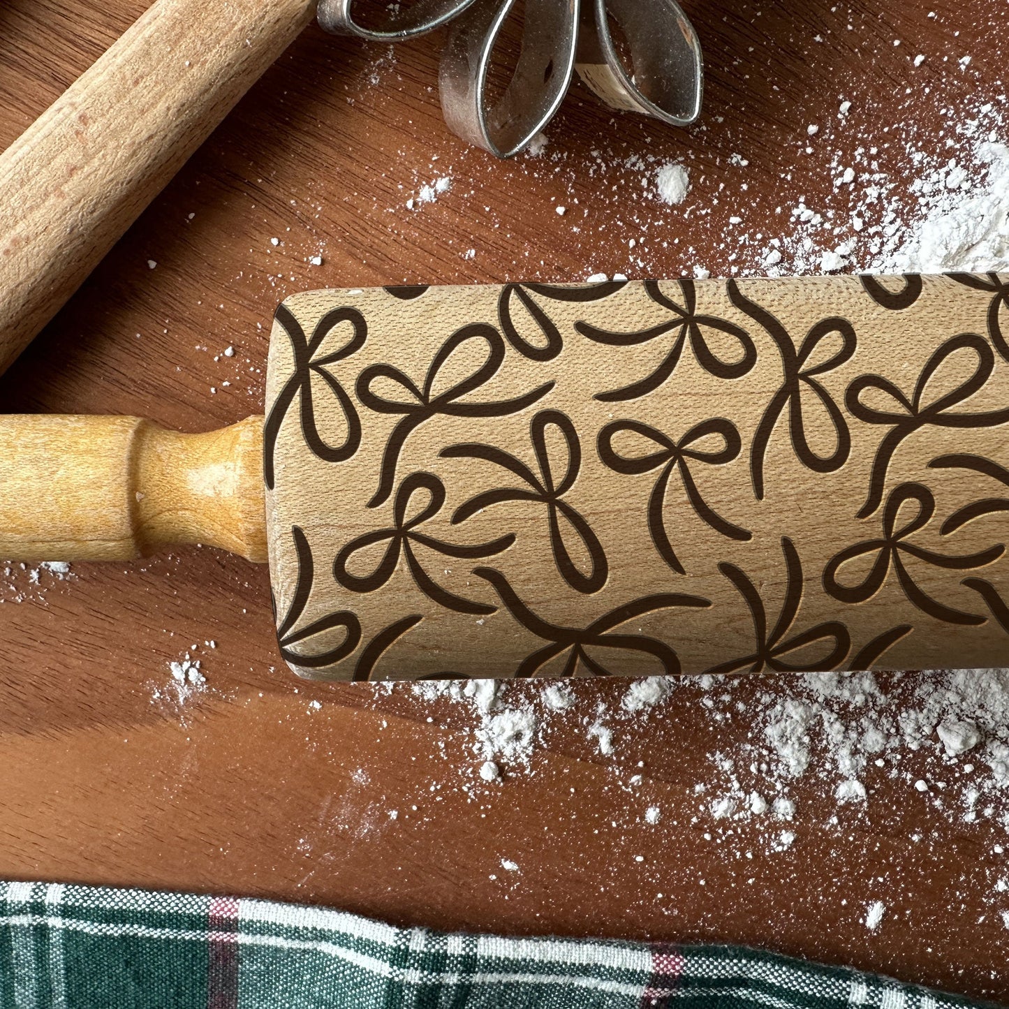 Wooden rolling pin with floral patterns on a wooden surface with flour.