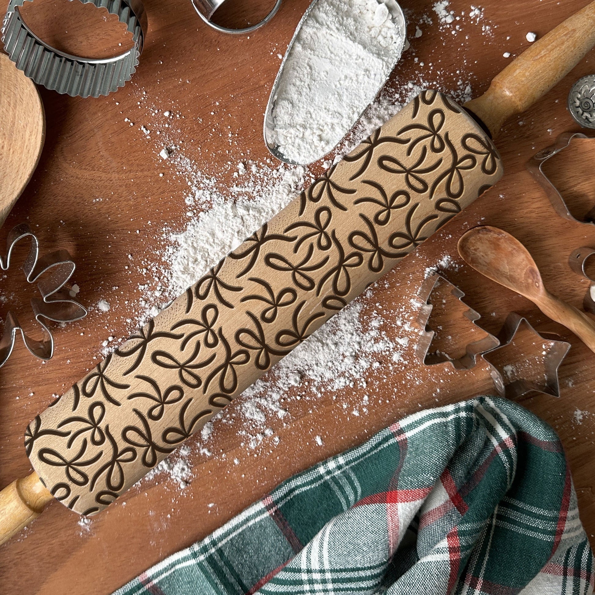Decorative rolling pin with patterns on a wooden surface with flour and baking tools.