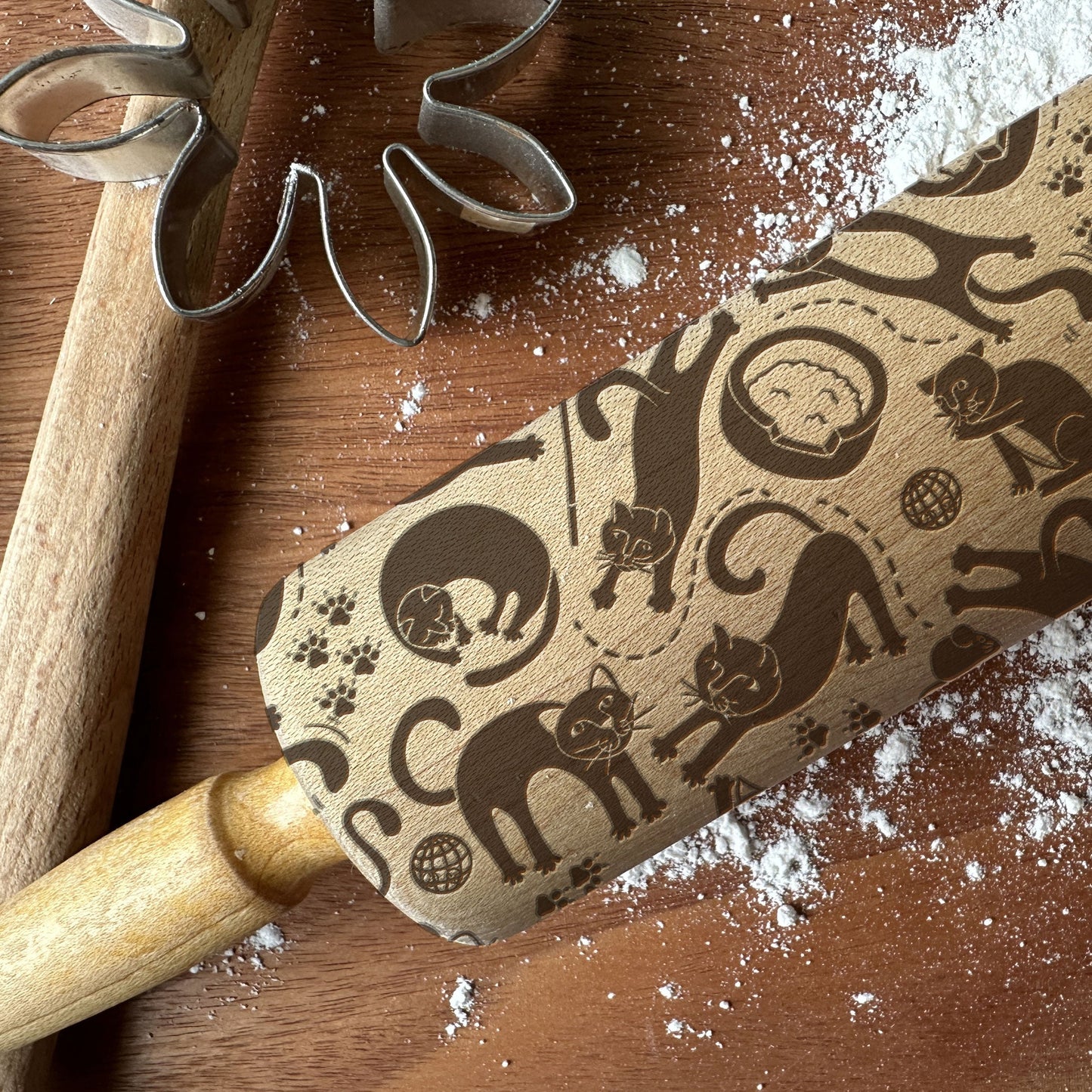 Rolling pin with cat pattern on a wooden surface with flour