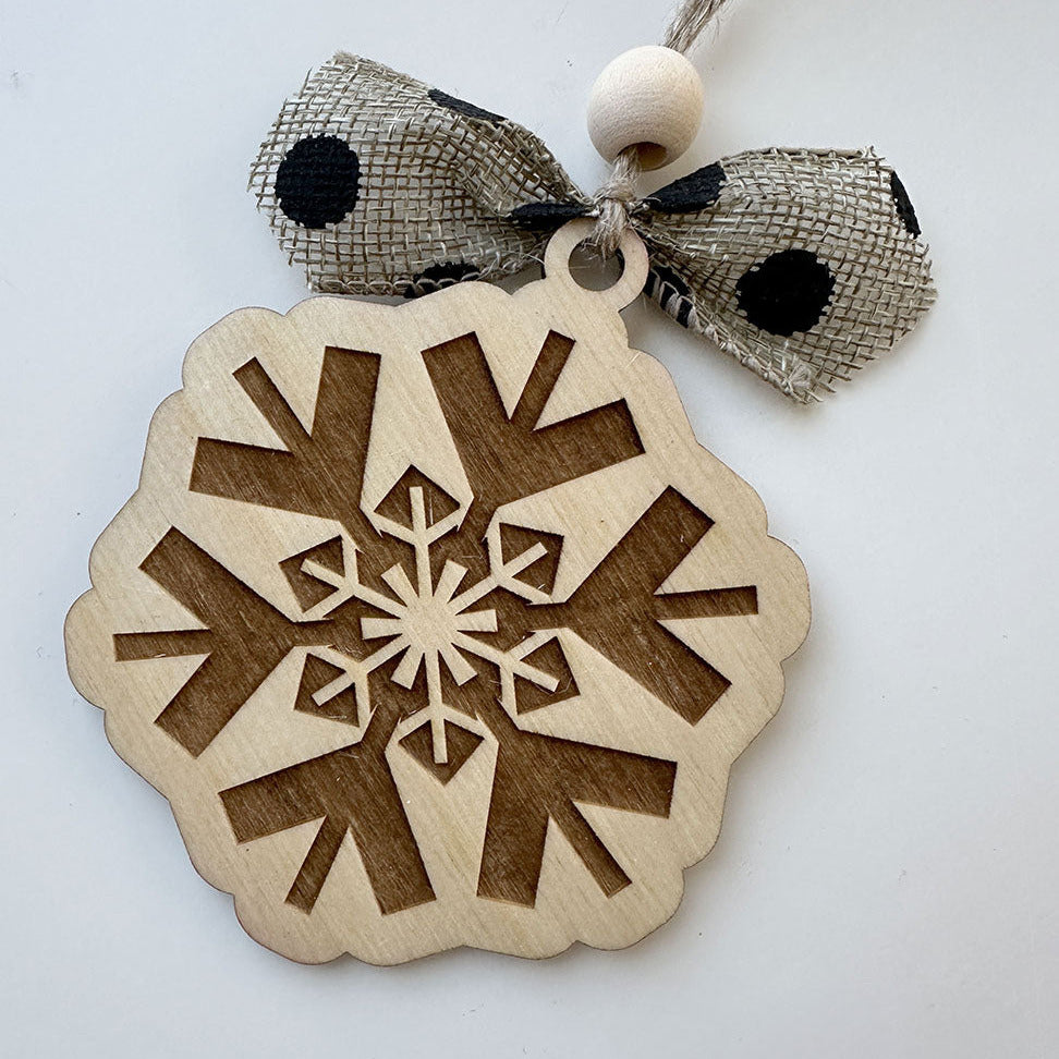 Wooden snowflake ornament with a ribbon on a white background
