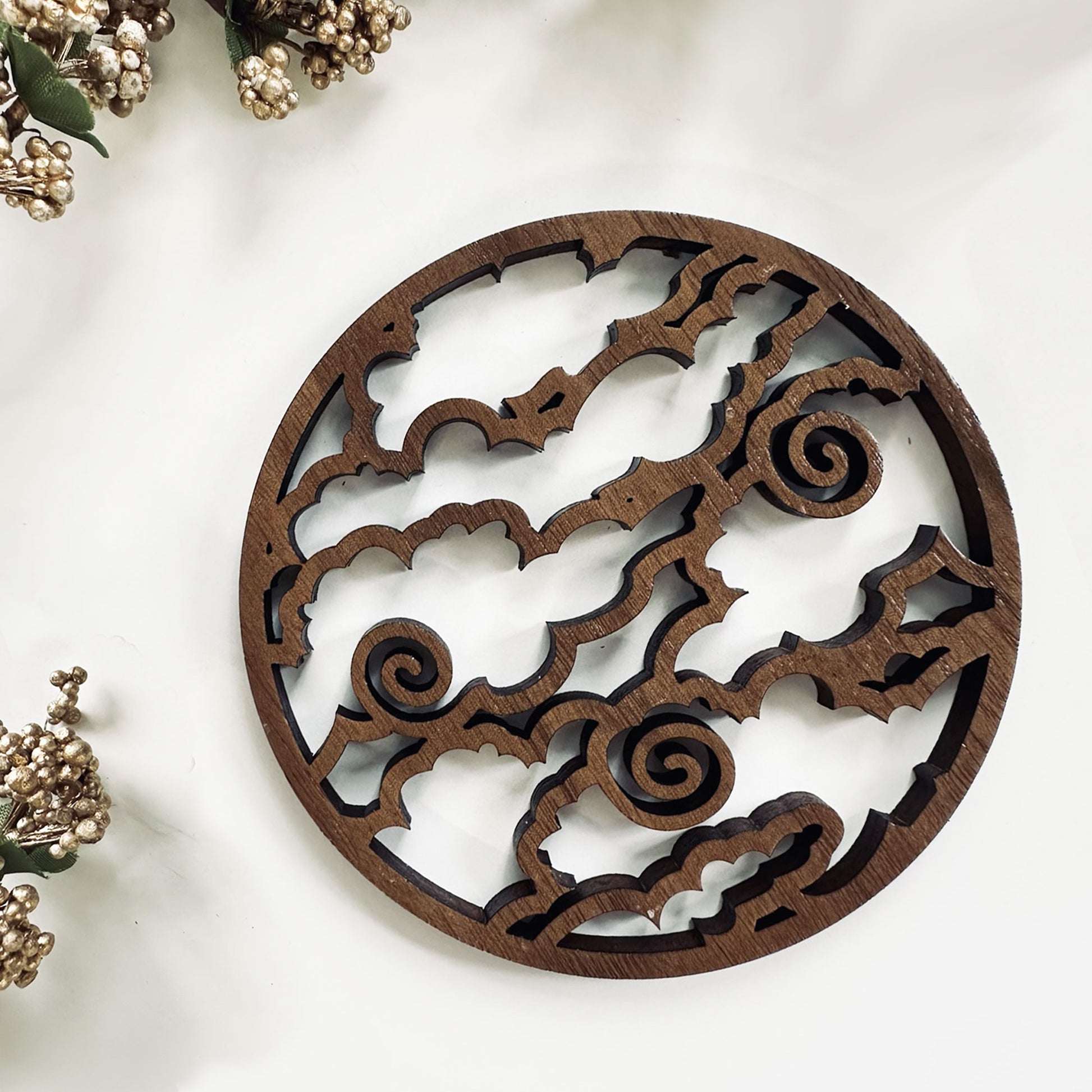 Decorative wooden coaster with intricate cut-out patterns on a white background