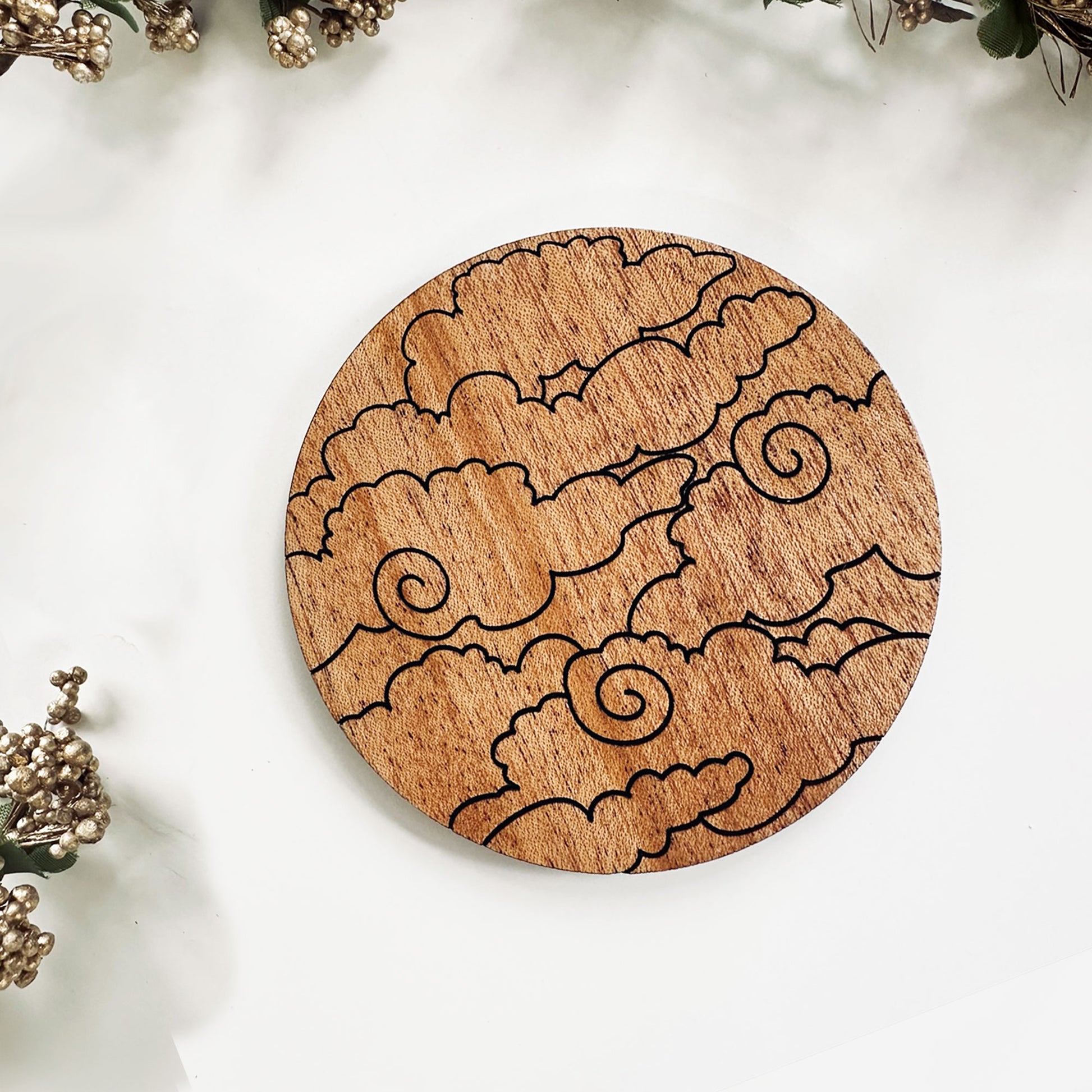 Wooden coaster with cloud design on a white surface