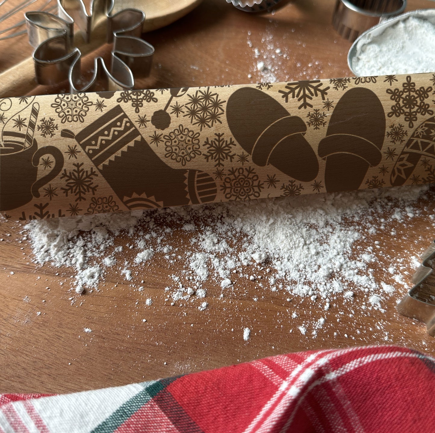 Decorative rolling pin with winter-themed design on a wooden surface with flour.