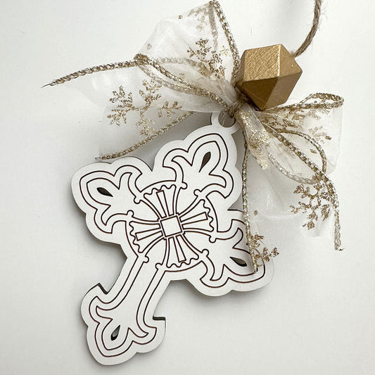 Decorative cross ornament with decorative string and gold cube on a white background