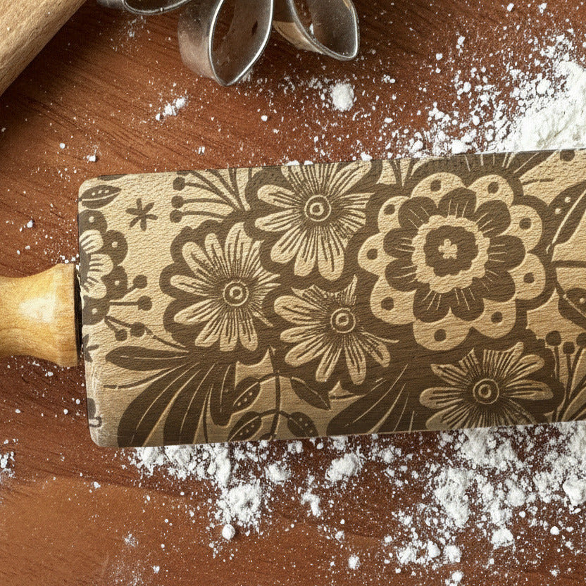 Decorative rolling pin with floral pattern on a wooden surface with flour, branded 'PickleandPeachStudio'.