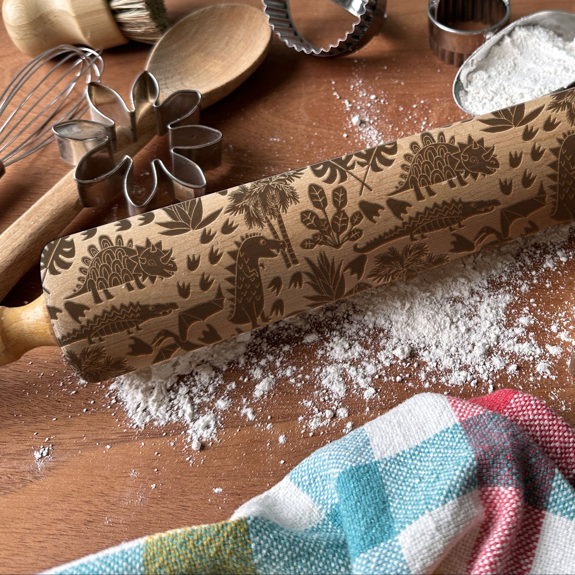 Decorative rolling pin with embossed patterns on a wooden surface with baking tools.