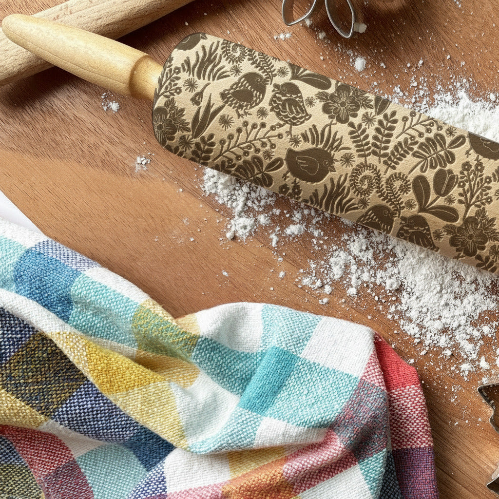 Decorative rolling pin with embossed patterns on a wooden surface with baking tools.