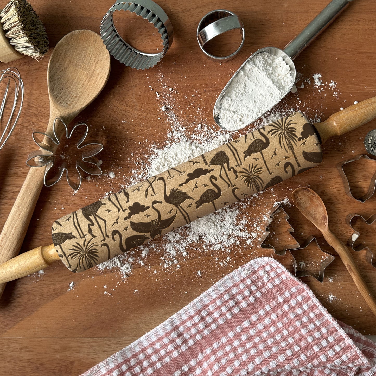 Baking tools including a rolling pin with embossed designs on a wooden surface.