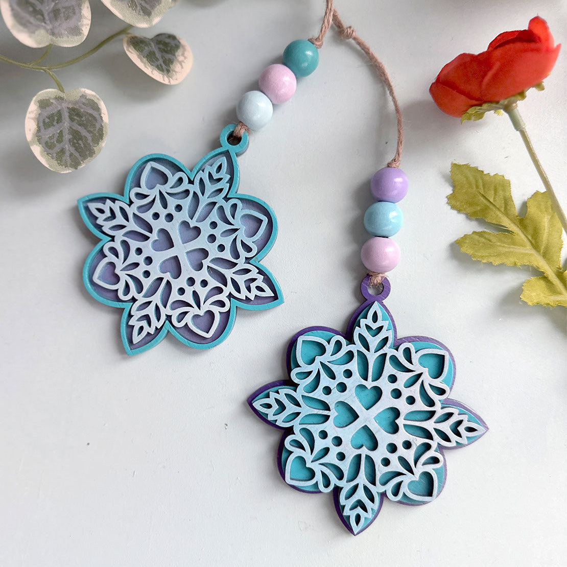 Decorative snowflake ornaments with beads on a white background with floral elements.