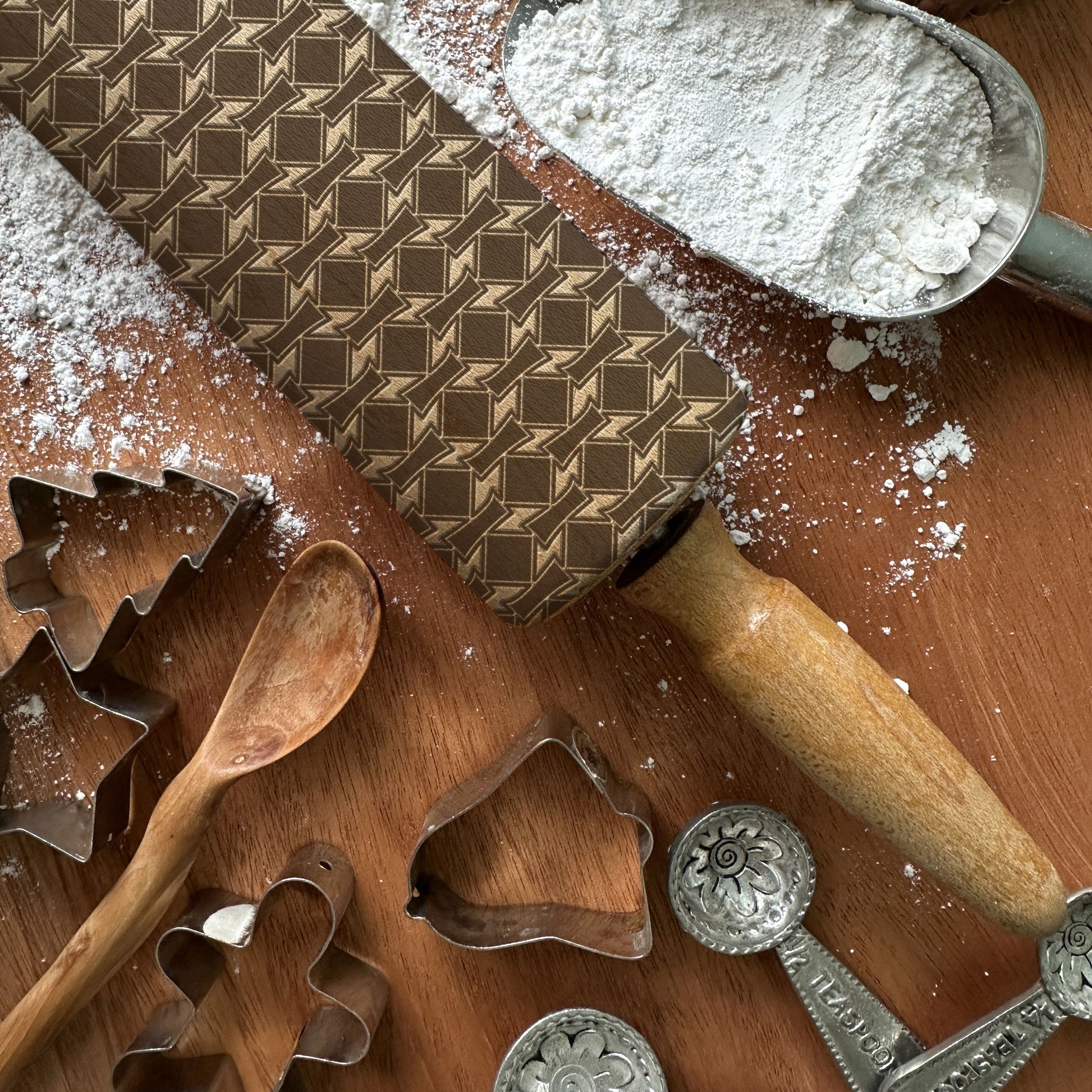Baking tools including a rolling pin, cookie cutters, and flour on a wooden surface.