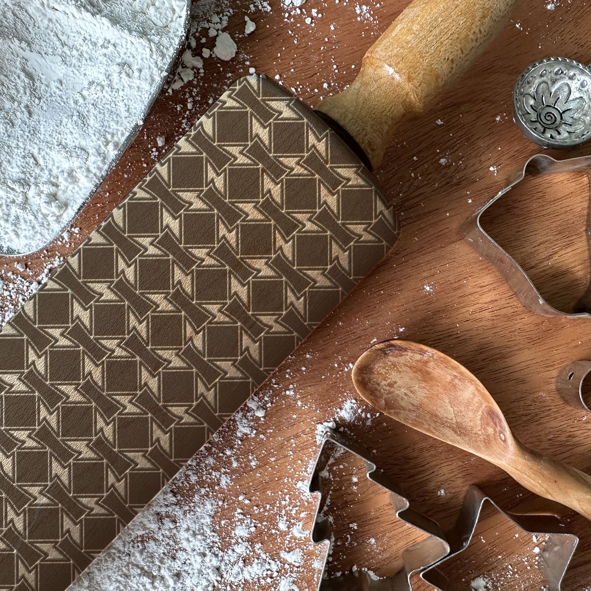 Baking tools and ingredients on a wooden surface with flour and cookie cutters.