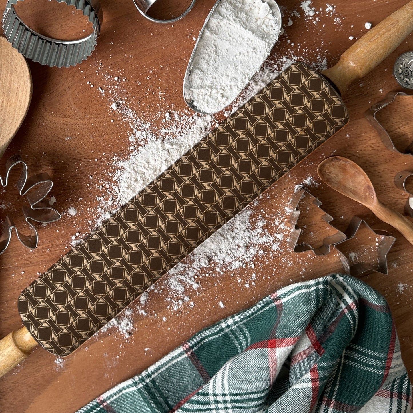 Wooden rolling pin with pattern, flour, and baking tools on a wooden surface.