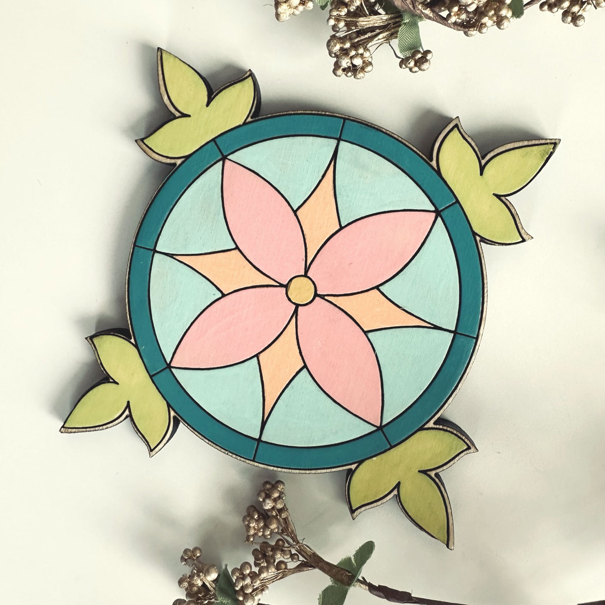 Decorative coaster with a pink flower and green leaves on a white background