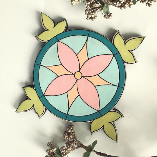 Decorative coaster with a pink flower and green leaves on a white background
