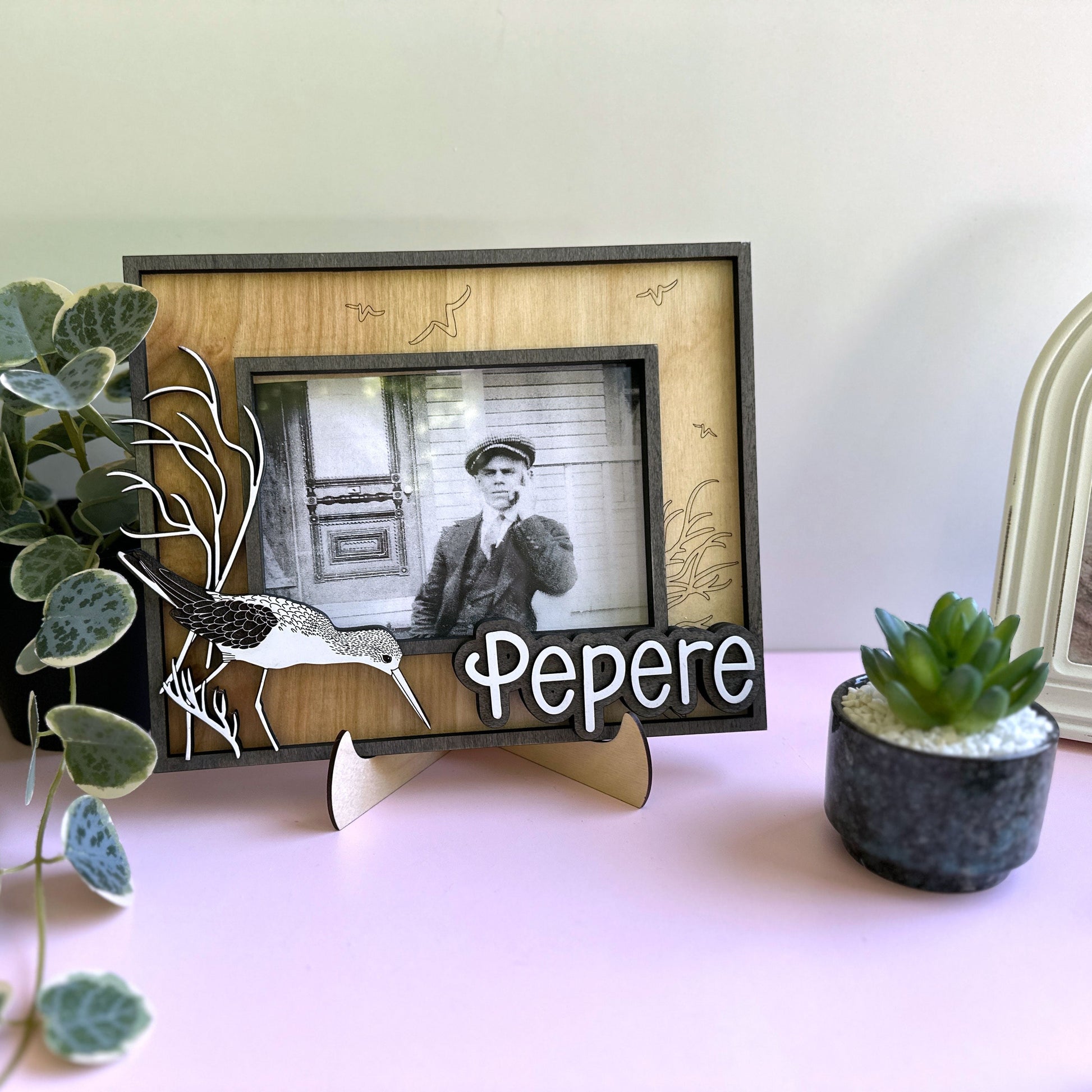 Framed photo of a man with 'Pepere' below, surrounded by plants on a table.