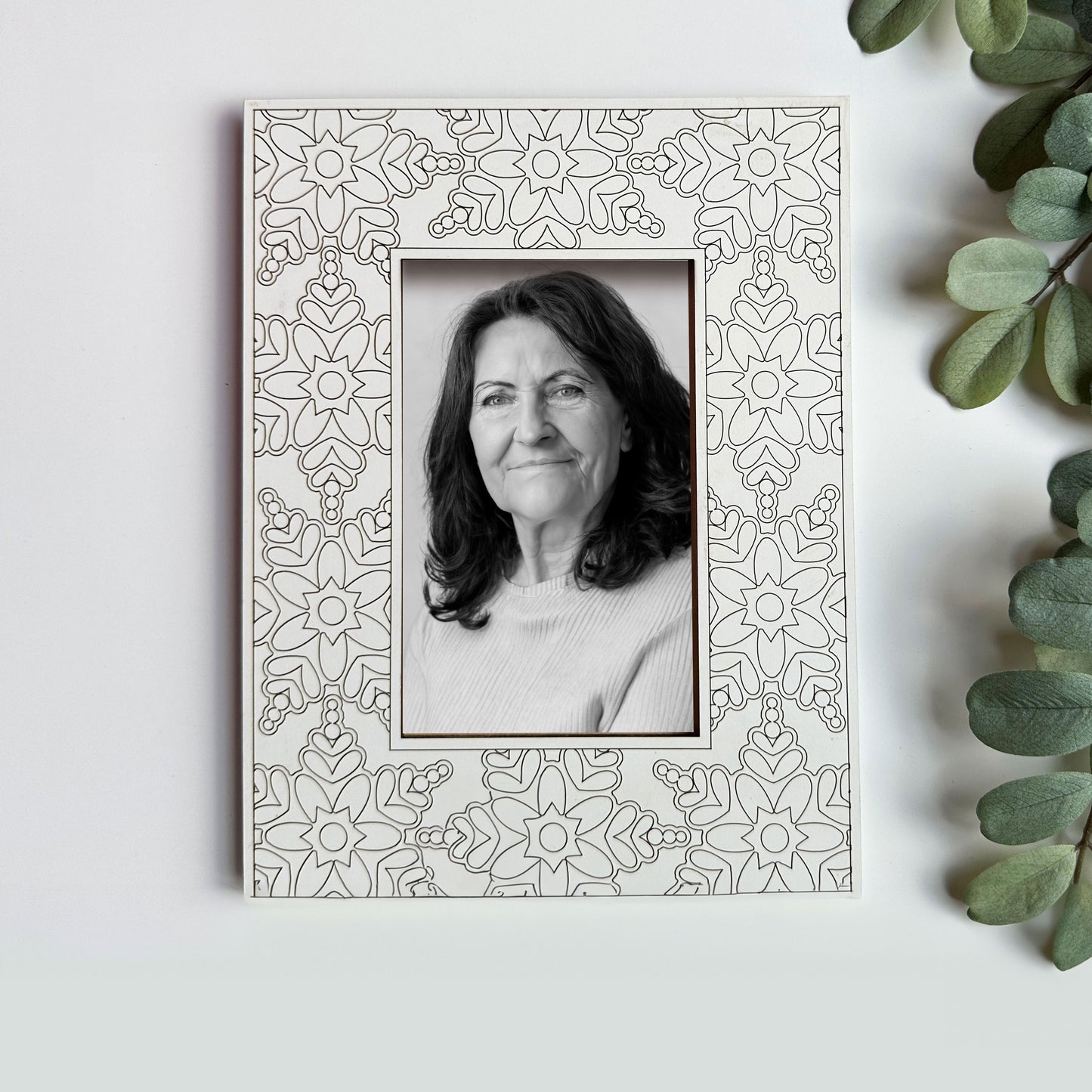 Decorative photo frame with a black and white portrait of a woman on a light background.