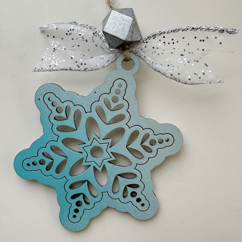 Decorative snowflake ornament with a silver bow on a white background