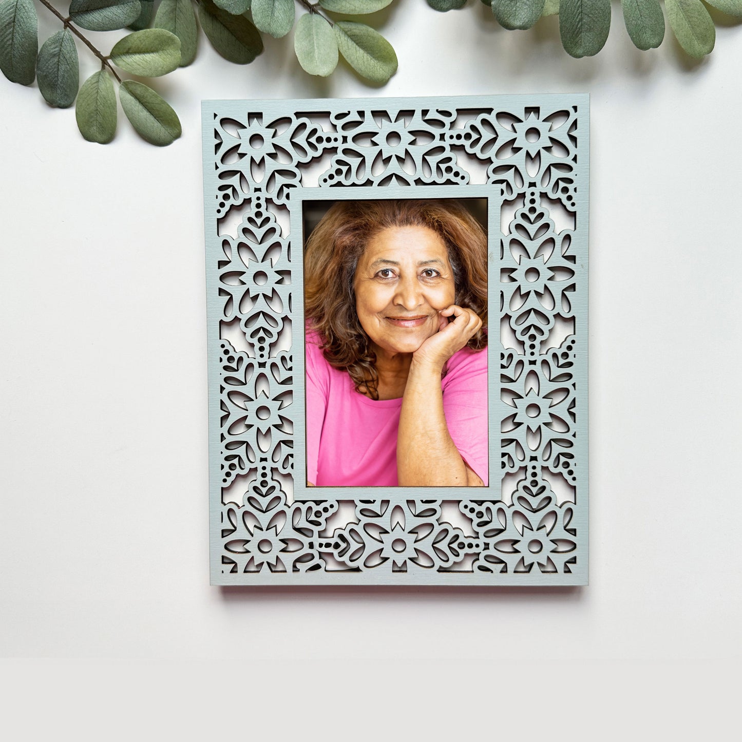 Decorative photo frame with a cut-out pattern containing a photo of a woman in a pink shirt.