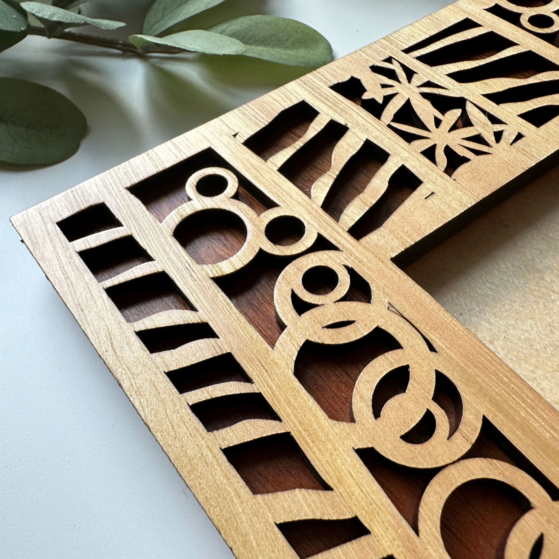 Wooden decorative panel with intricate cut-out patterns on a light background