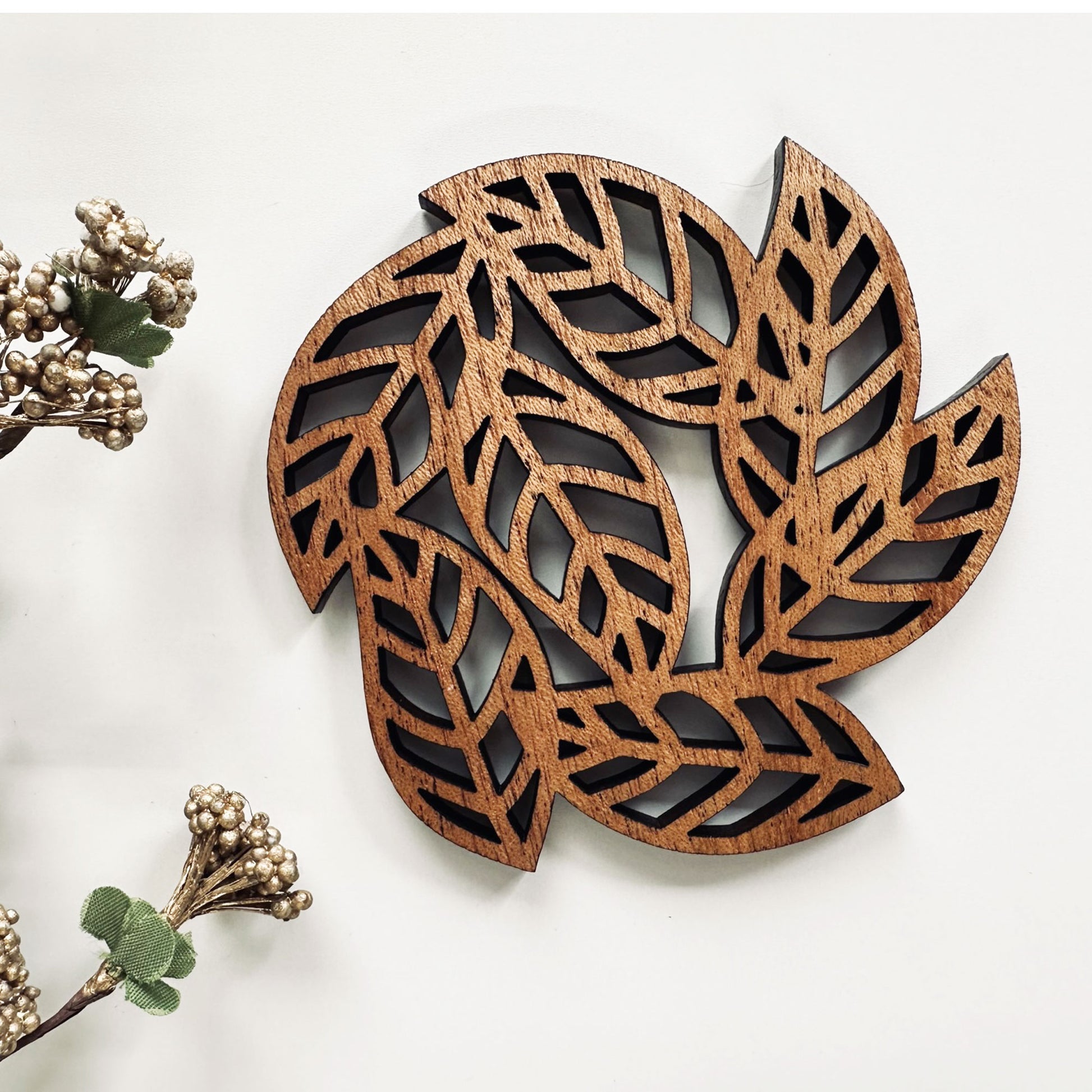 Wooden leaf-shaped decorative coaster with cut-out patterns on a white background