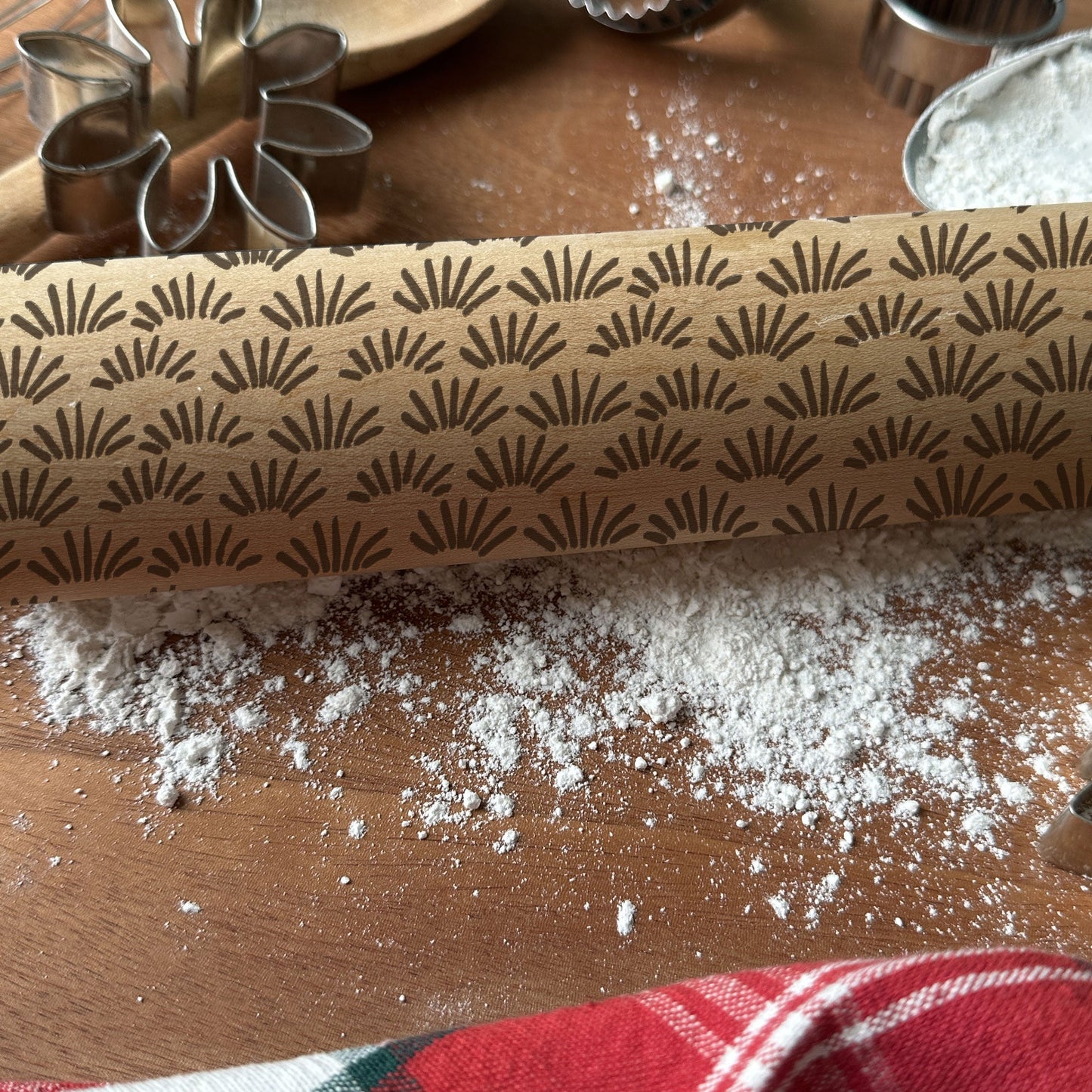 Rolling pin with decorative pattern on a wooden surface with flour