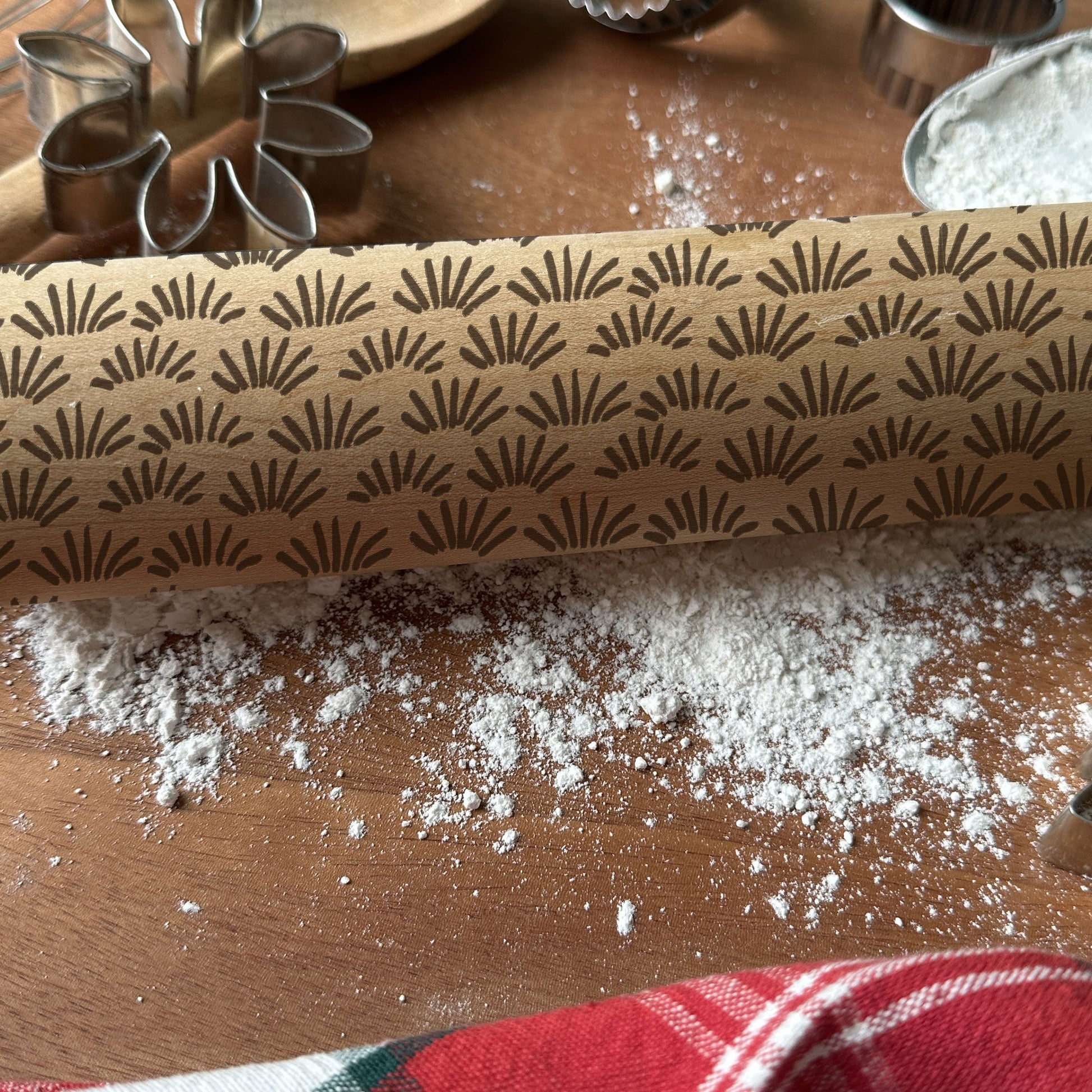 Rolling pin with decorative pattern on a wooden surface with flour