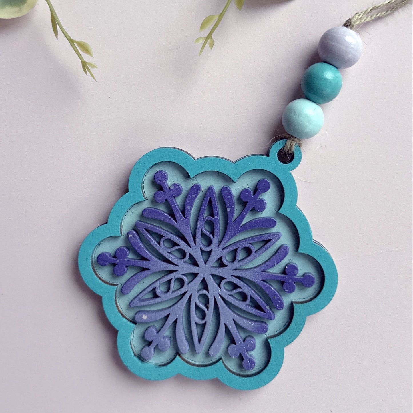 Blue and purple snowflake ornament with beads on a white background