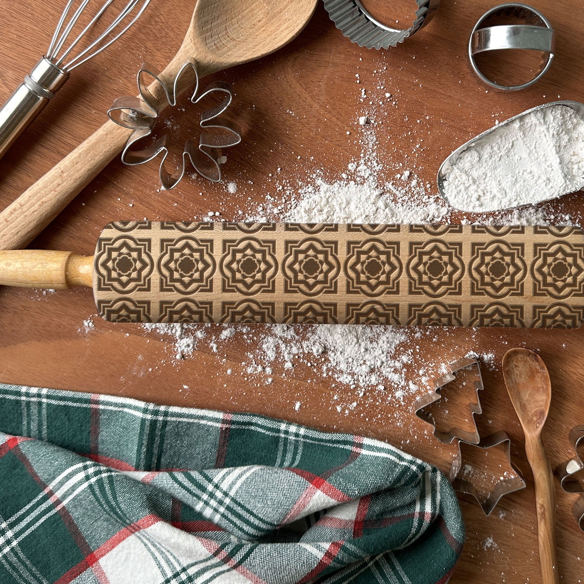 Wooden rolling pin with decorative patterns on a wooden surface with baking tools and flour.